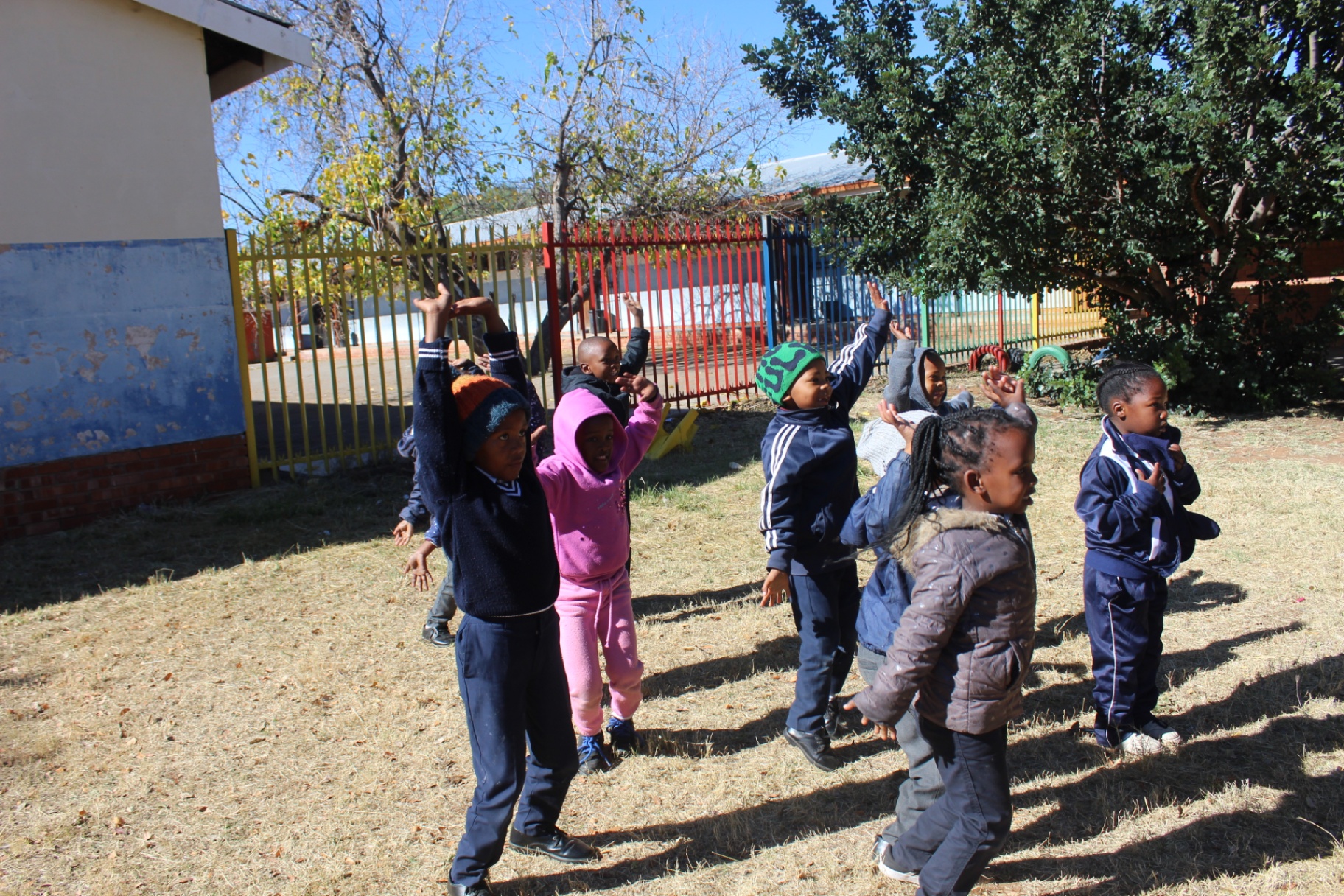Children stretching their arms overhead during an outdoor warm-up