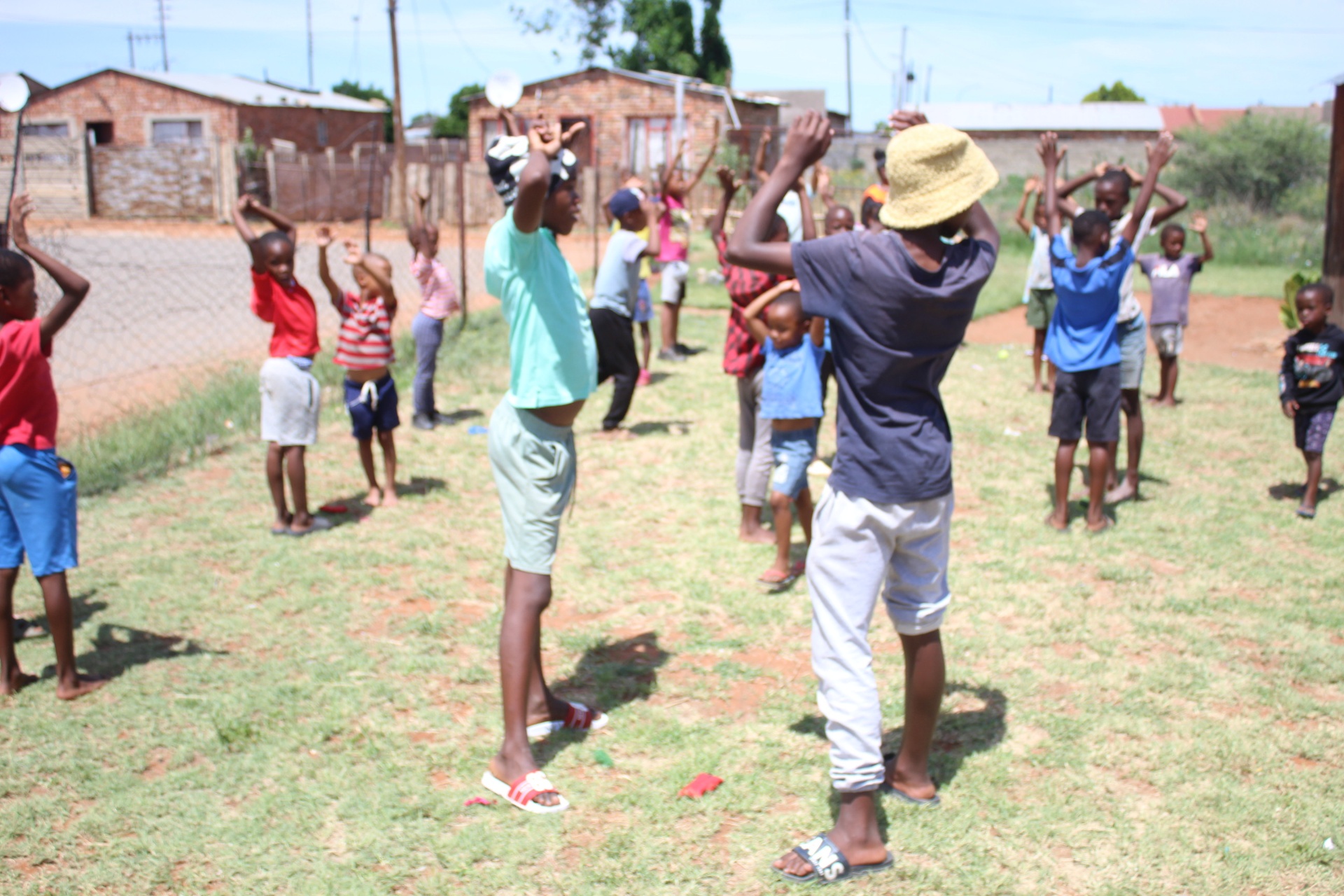 Children stretching their arms overhead during a Come N Play outdoor warm-up session