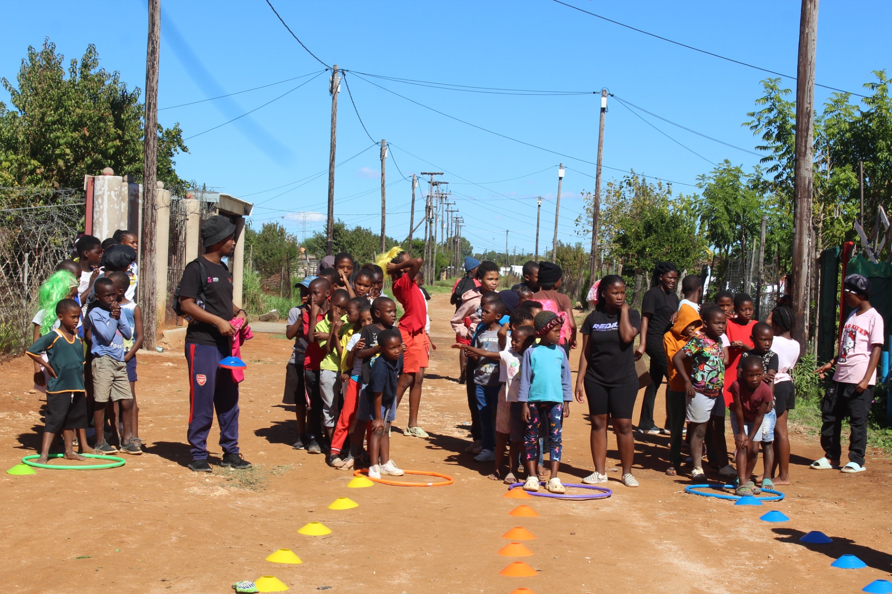Community outreach session with children lined up at agility cones and hoops in Kimberley