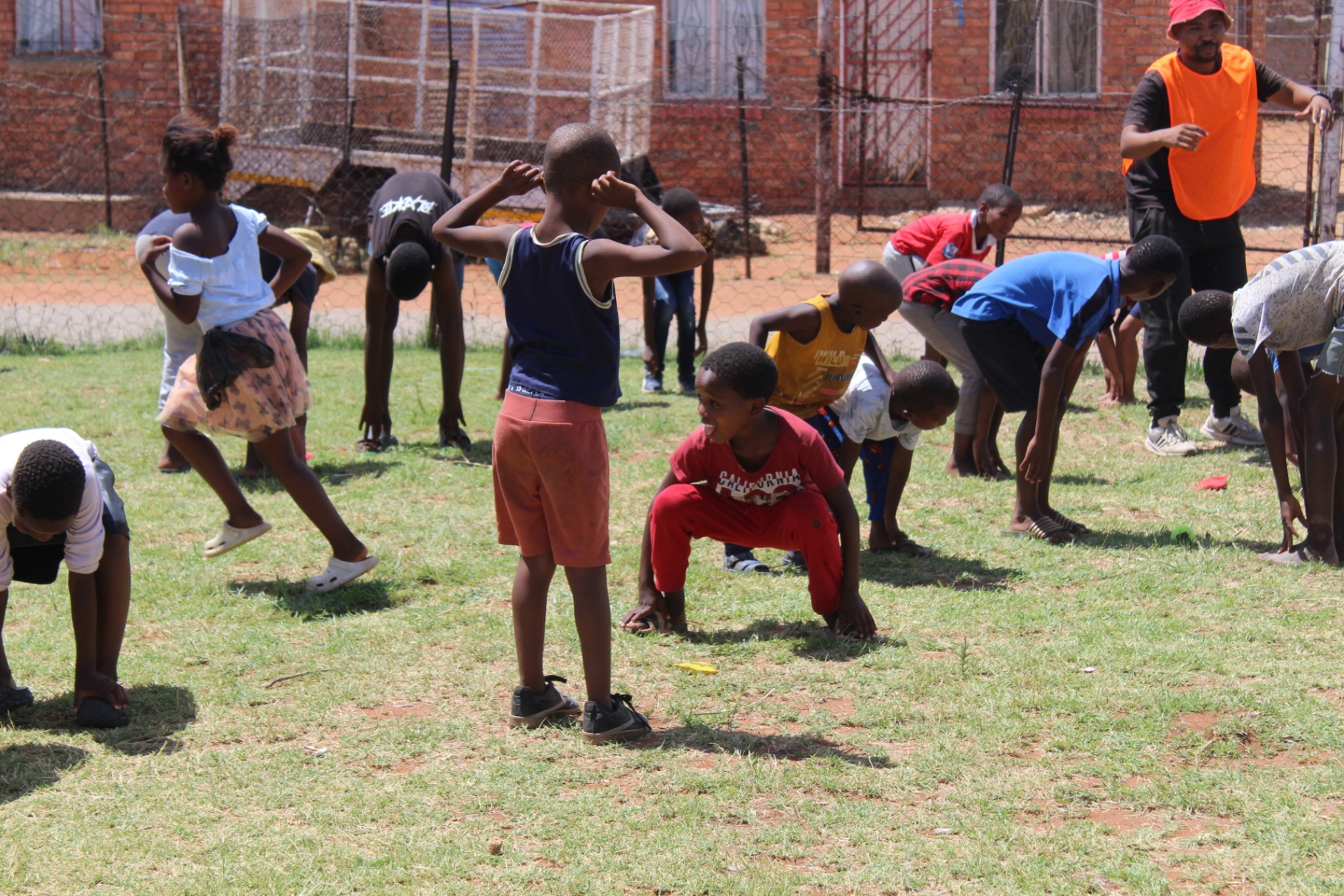 Children doing stretching exercises on the grass during a Come N Play sports session