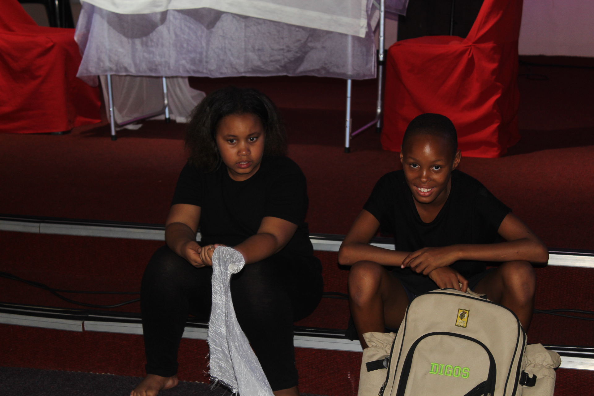 Two children backstage on the red church stage during a Come N Play Theatre 2 Church production